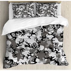 a bed with white sheets and black and white camo print on the comforter