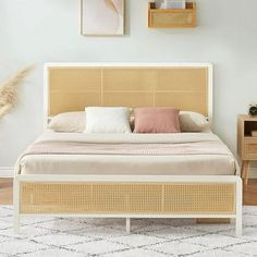 a bed with wicker headboard and foot board in a white room next to two pictures on the wall