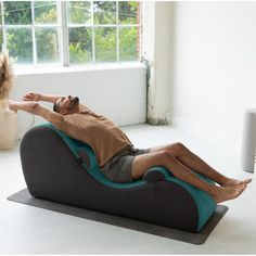 a man laying on top of a bean bag chair in front of a large window