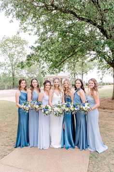 a bride and her bridal party posing for a photo in front of a tree