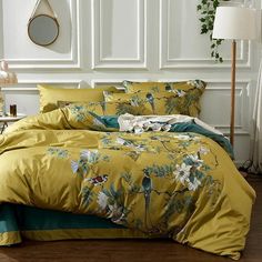 a bed with yellow and green comforters in a white room next to a plant