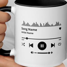 a person holding a white and black coffee mug with an audio player on the side