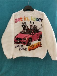 a white sweater with the words get in laser and an image of a dog driving a car