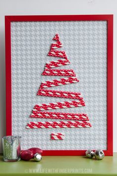 a christmas tree made out of yarn is displayed in a red frame on a table