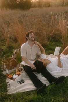 a man and woman laying on a blanket in the grass