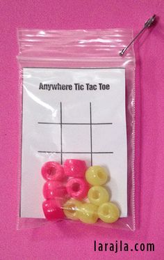 there is a plastic bag with some beads in it on the pink surface, and an adhesivee tag too