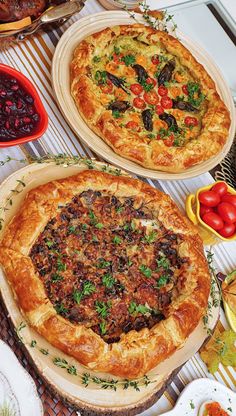 two pizzas sitting on top of a table covered in toppings