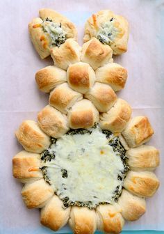 bread rolls with cheese and spinach spread on top, arranged in the shape of a flower