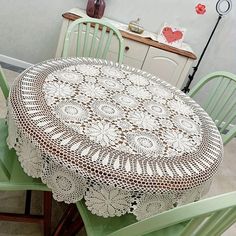 two green chairs and a table with a doily on it