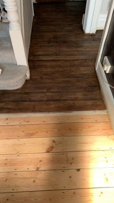 an overhead view of a wood floor and stairs in a house with sunlight coming through the door