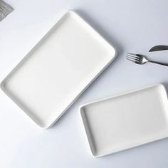 two white plates with forks and spoons next to each other