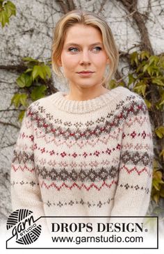 a woman standing in front of a tree wearing a sweater