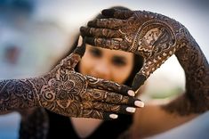 a woman holding up her hands with henna tattoos on it's arms and arm