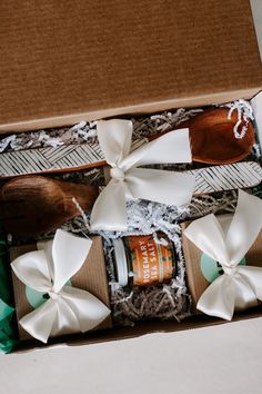 an open box containing two wooden spoons, salt and pepper shakers with white bows