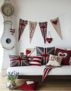 a living room filled with lots of pillows and flags hanging from the wall next to a clock