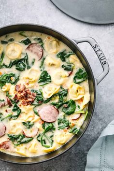 a pan filled with pasta and spinach covered in cheese