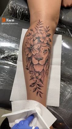 a woman's leg with a lion and flowers tattoo on it