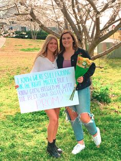 two women standing next to each other holding a sign