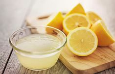 a wooden cutting board topped with sliced lemons next to a bowl of liquid on top of it