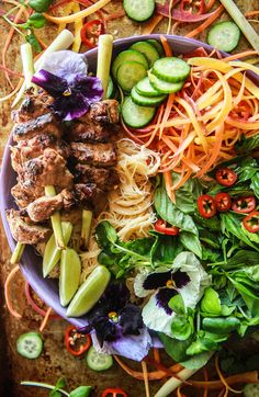 a purple plate topped with meat and veggies next to sliced cucumbers