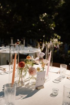 the table is set with clear vases, flowers and candles for an elegant wedding reception