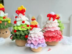 small crocheted christmas trees sitting on top of a white table next to candy canes