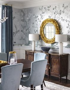 an elegant dining room with blue chairs and wallpaper