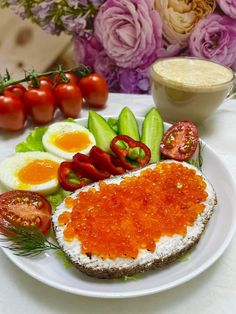 a white plate topped with an egg, tomato and cucumber next to flowers