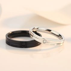 two black and white wedding bands with diamond stones on each band, sitting next to each other