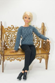 a barbie doll sitting on a wooden bench