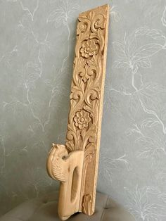 a carved wooden cat sitting on top of a chair in front of a wallpapered wall