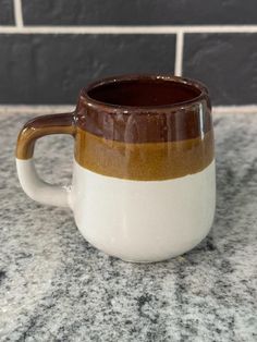 a brown and white coffee mug sitting on top of a counter