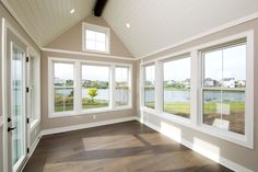 an empty room with three large windows and wood flooring on the side of the room