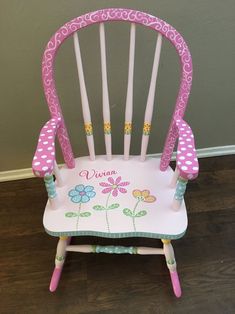 a child's wooden rocking chair with pink and white flowers on the seat, decorated with polka dots