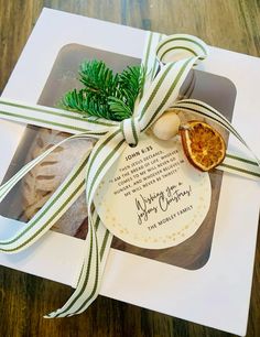 an orange slice tied with a green ribbon on top of a white box that says merry christmas