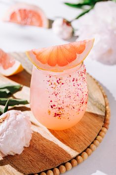 a grapefruit cocktail with orange slices and sprinkles on the rim