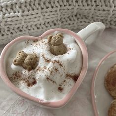 two heart shaped mugs filled with whipped cream and teddy bears