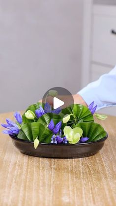 a person placing flowers in a bowl on a table