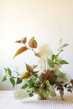 a vase filled with lots of flowers on top of a table