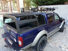 a blue pick up truck parked in front of a building with a bike rack on the back