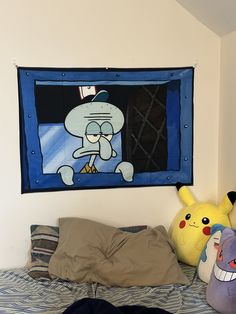 a bed with two stuffed animals on top of it and a cartoon wall hanging above the bed