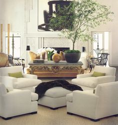 a living room filled with white furniture and a potted plant on top of a table