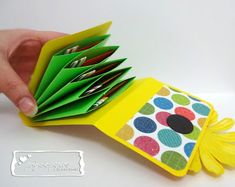 a hand holding an open book with lots of papers in it and a yellow cover