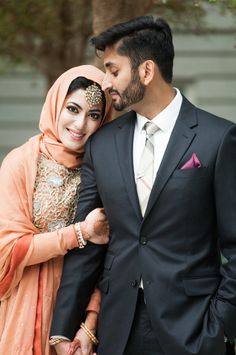 a man in a suit and tie standing next to a woman wearing a headscarf