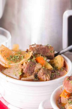 a white bowl filled with beef stew and carrots next to an instant pressure cooker