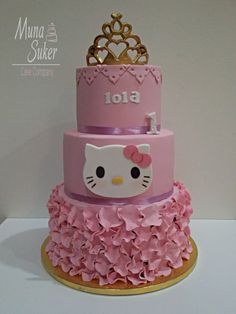 a hello kitty birthday cake with pink ruffles and a gold crown on top