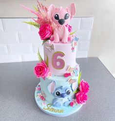 a pink and blue birthday cake with lillies on top