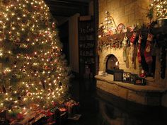 a christmas tree is lit in front of a fireplace