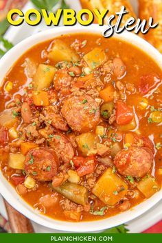 a white bowl filled with stew and potatoes on top of a red table cloth next to bread