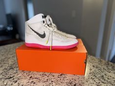 a pair of white and pink nike shoes on top of an orange box